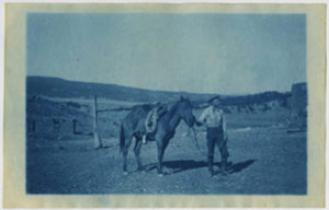Blue tinted photograph of a cowboy leading his horse