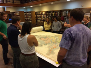 A geology class in the special collections reading room learn about an item called the Smith map.