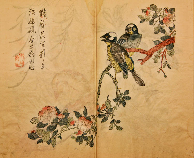 Two birds sit on a tree branch with flowers. Chinese lettering in upper left corner.