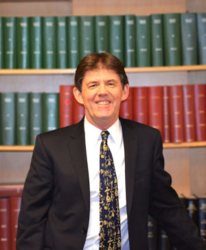 The library's dean, Kevin Mulroy, stands in front of bound journals.