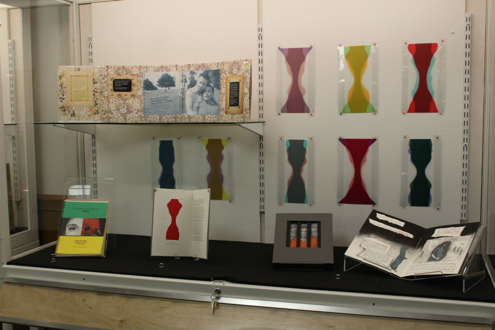 Several artist's books and diagram from one book are shown in an exhibit case.