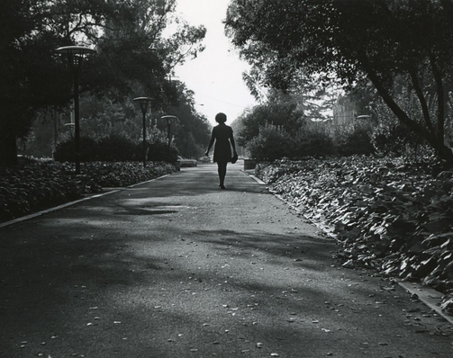 Photo of Myrlie Evers-Williams walking down a path lined with trees and other vegetation